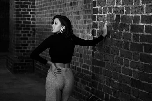 Portrait of a beautiful sensual redhead girl posing in sunset sunlight wearing light jersey trousers and black long sleeve t shirt
