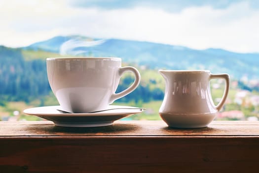 Coffee with milk in ceramic cup with small milk jug