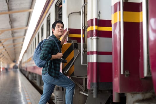Excited for his next adventure, a young man prepares to board a train, highlighting the thrill of travel and the journey ahead with his camera in tow.