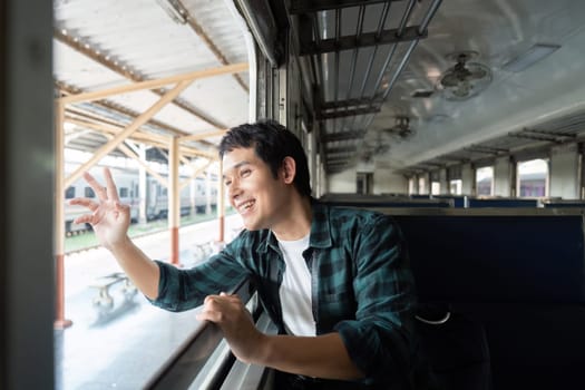 With a smile on his face, the young man watches the landscape pass by during his train ride, reflecting the joy and excitement of traveling.