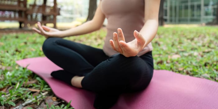 A peaceful moment of meditation as a woman sits cross-legged on a yoga mat, focusing on her breath amidst the natural surroundings. This tranquil scene highlights mindfulness and inner peace.
