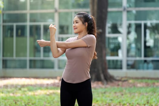 In a tranquil outdoor environment, a woman continues her fitness journey with focused arm stretches, enhancing flexibility and overall wellness.