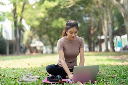 A modern depiction of work-life balance as a woman sits on a yoga mat, using her laptop in nature, blending productivity and wellness in her lifestyle.