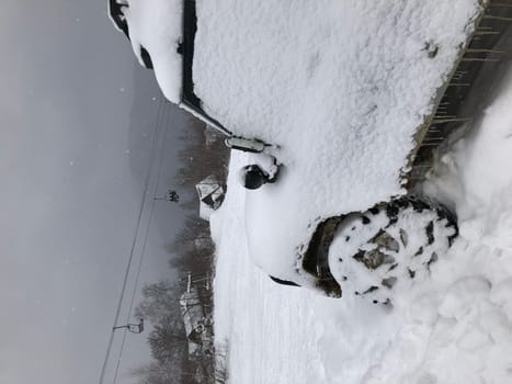 Snow covered SUV car parked outdoor on a winter ski slope in the mountains