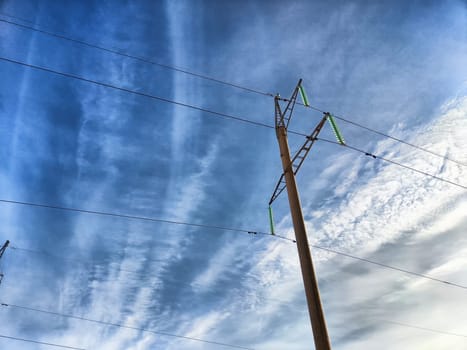 Power lines stand tall against a vibrant and textured sky filled with clouds during the late afternoon.