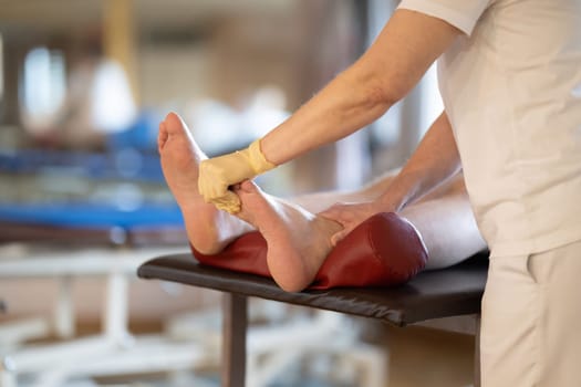 A physiotherapist treating a patients foot in a busy rehabilitation center, focusing on recovery and mobility improvement.