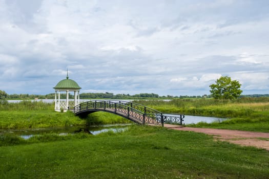 Veliky Novgorod, Russia - 07.30.24. Anna's Gazebo and the graceful bridge over the channel. Vitoslavlitsy Museum-Reserve.