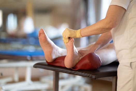 A physiotherapist treating a patients foot in a busy rehabilitation center, focusing on recovery and mobility improvement.