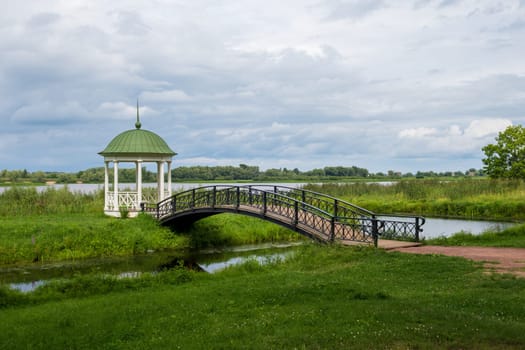 Veliky Novgorod, Russia - 07.30.24. Anna's Gazebo and the graceful bridge over the channel. Vitoslavlitsy Museum-Reserve.