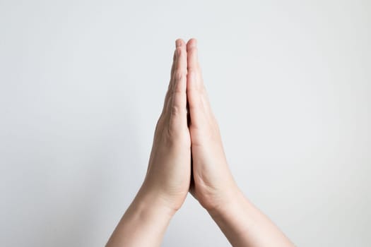 Close up of caucasian adult hands in prayer gesture against white background.