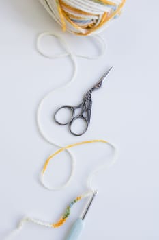 Colorful yarn and crochet tools on white surface. Creative arts and crafts scene.