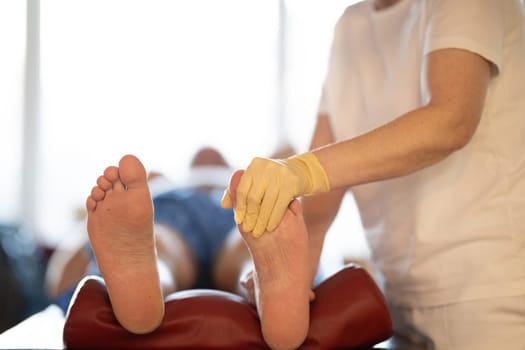 A physiotherapist treating a patients foot in a busy rehabilitation center, focusing on recovery and mobility improvement.