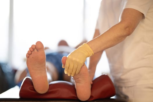A physiotherapist treating a patients foot in a busy rehabilitation center, focusing on recovery and mobility improvement.