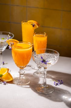 Elegant glasses filled with vibrant orange cocktails, garnished with edible flowers and orange slices, create a refreshing and visually appealing scene