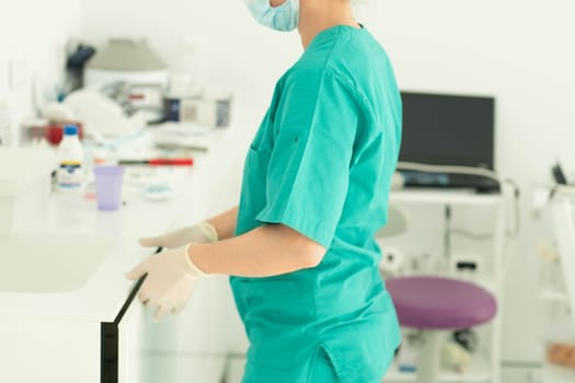Dental assistant in glove and mask and uniform cleaning dental office