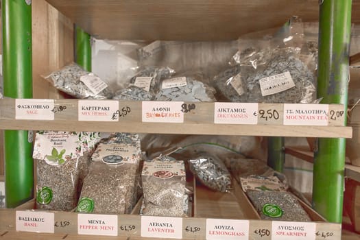 Crete.Greece - april 02, 2025: Herb packets with Greek and English labels including sage, bay leaves, and mountain tea, neatly arranged on wooden shelves in a rustic shop interior.