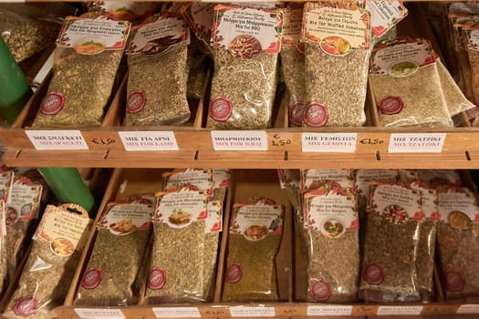 Crete.Greece - april 02, 2025: Culinary herb bags labeled with names like "Mix for BBQ" and "Mix for Tzatziki," displayed neatly on wooden shelves, emphasizing variety and cultural flavors.