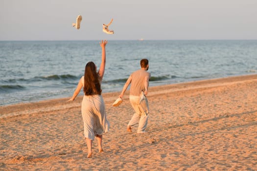 Girl throws sandals up in the ocean. Beginning of holidays, honeymoon