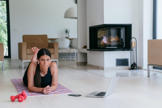 Young woman resting after online training while lying on the living room floor