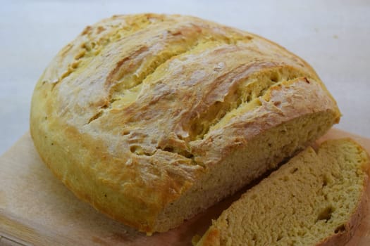 A loaf of freshly baked bread with a golden brown crust and a soft, airy interior, sliced open on a wooden cutting board, showcasing its perfect texture and inviting aroma.