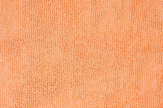 Microfiber cleaning cloth surface texture close up showing the looped pile of the fabric in vivid orange color, ideal for backgrounds and textures