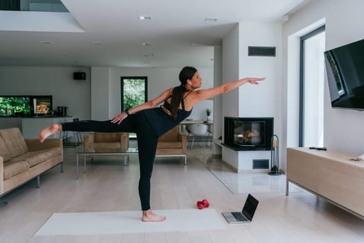 Young Beautiful Female Exercising, Stretching and Practising Yoga with Trainer via Video Call Conference in Bright Sunny House. Healthy Lifestyle, Wellbeing and Mindfulness Concept.