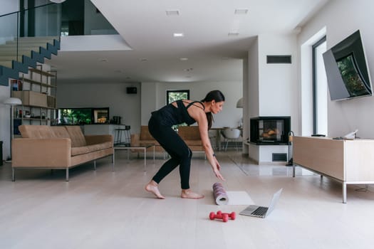Young Beautiful Female Exercising, Stretching and Practising Yoga with Trainer via Video Call Conference in Bright Sunny House. Healthy Lifestyle, Wellbeing and Mindfulness Concept