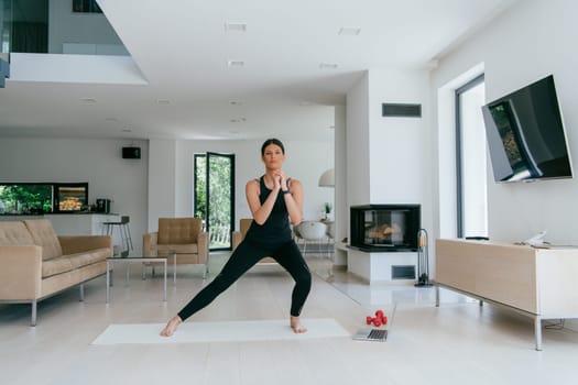 Young Beautiful Female Exercising, Stretching and Practising Yoga with Trainer via Video Call Conference in Bright Sunny House. Healthy Lifestyle, Wellbeing and Mindfulness Concept.