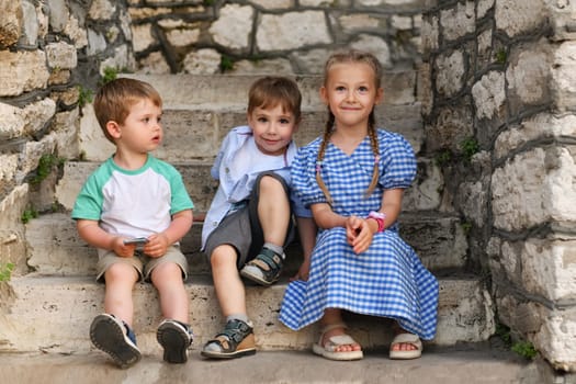 Children friends brothers and sister on the steps in the park