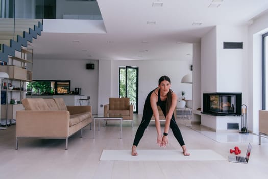 Young Beautiful Female Exercising, Stretching and Practising Yoga with Trainer via Video Call Conference in Bright Sunny House. Healthy Lifestyle, Wellbeing and Mindfulness Concept.