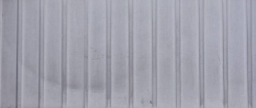 Gray metal siding texture with vertical lines. The siding has a matte finish and a slightly weathered appearance
