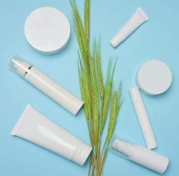 White plastic tubes, jars and bottles for cosmetics on blue background