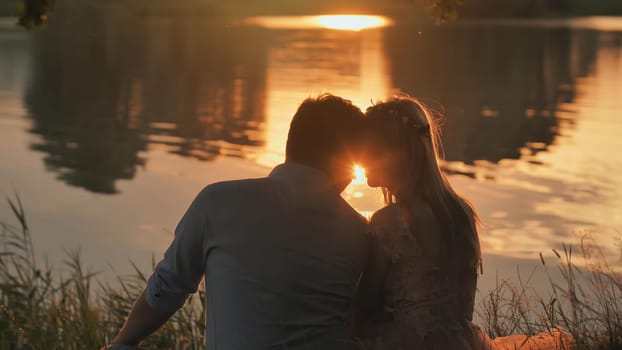 A young couple sits on a lake at sunset