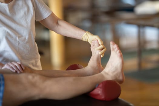 A physiotherapist treating a patients foot in a busy rehabilitation center, focusing on recovery and mobility improvement.
