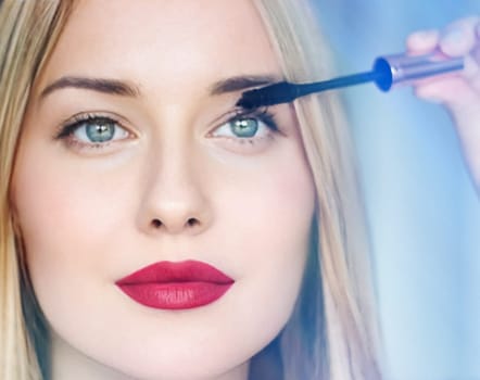 Woman applying mascara with confidence, defined brows and red lipstick. Blonde beauty focused on her eye makeup, cosmetics look