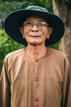 Portrait of an elderly old male senior Asian Vietnamese farmer in hat in a field in Vietnam in Asia. Nha Trang, Vietnam - December 20, 2024