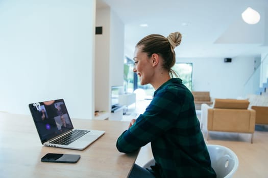 A woman sitting in the living room using a laptop is looking at cam talk by video call with business friends and relatives. The headshot is Job interview answering questions.