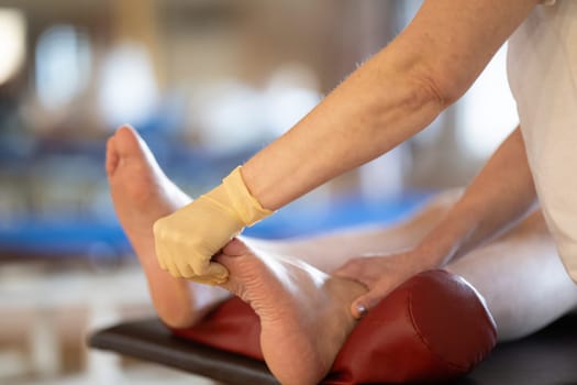 A physiotherapist treating a patients foot in a busy rehabilitation center, focusing on recovery and mobility improvement.