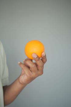 A close-up shows a hand holding a vibrant orange fruit, symbolizing freshness.