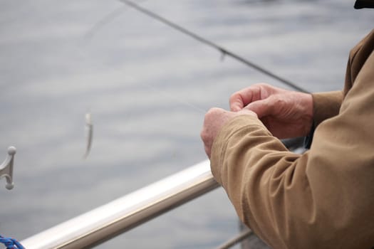 A person expertly ties fishing tackle on a boat during early morning.