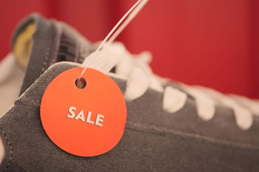 Gray sneakers with a sale tag displayed prominently in a store setting.