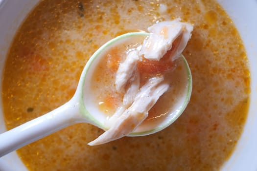 A spoonful of hearty chicken soup showcases tender meat and broth.