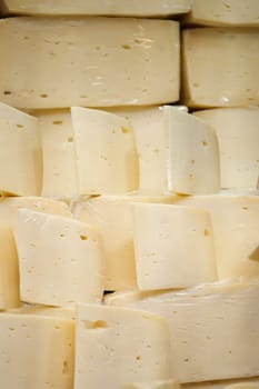 Various blocks of fresh cheese are neatly arranged in a market display.