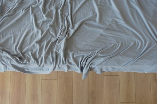 Wrinkled gray sheets are tossed on a bed in a relaxed setting.