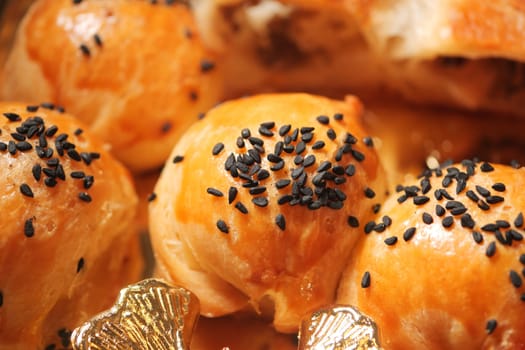 Delicious pastries topped with black sesame seeds await customers in a bakery.