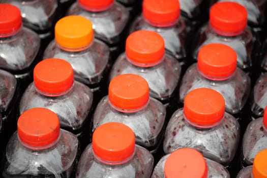 Numerous bottles with orange caps are arranged orderly for sale.