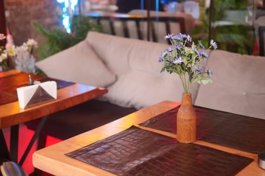 A tranquil dining space featuring a simple flower vase and leather placemats.