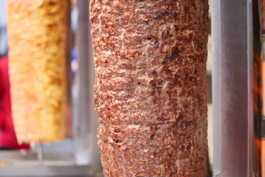 Juicy layers of seasoned meat slowly cook on a vertical grill at dusk.