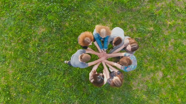 The concept of friendly friends and teamwork. Cheerful friends join hands in the center and scatter. View from above