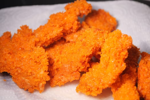 Golden crispy chicken strips garnished with a bright orange coating.